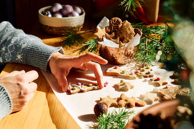 Woman's hands decorating glazed christmas gingerbread cookies.