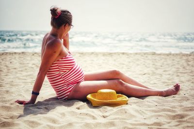 Pregnant woman sitting at beach