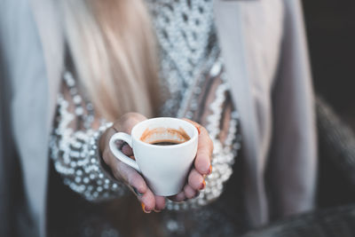 Girl sipping black coffee in cafe closup. woman holding white cup of coffee outdoors. good morning.