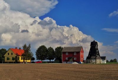 Houses on field by buildings against sky