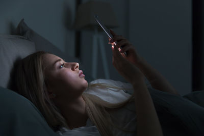 Woman looking away while relaxing on bed at home