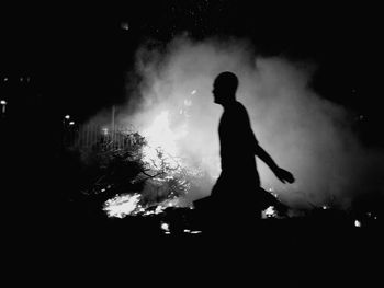 Silhouette man with arms outstretched at night