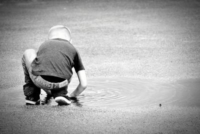 Rear view of boy playing in puddle on road