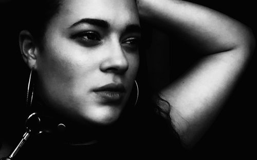 Close-up of young woman against black background