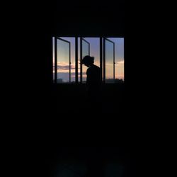 Silhouette people looking through window at home