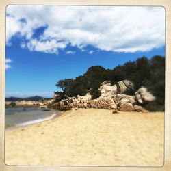 Scenic view of rocky beach against cloudy sky