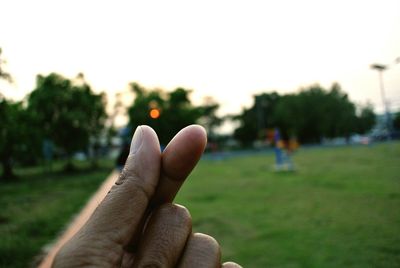 Cropped image of hand snapping fingers against tree