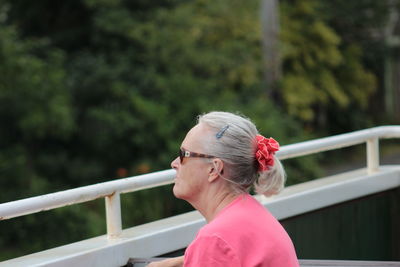 Portrait of woman standing against railing