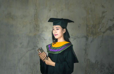 Smiling young woman standing against wall