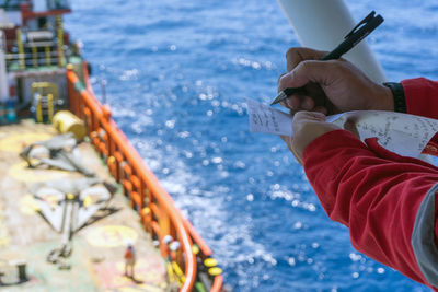 Midsection of person holding sailboat in sea