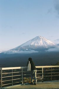 Man standing on snowcapped mountain against sky