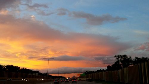 People on street against sky during sunset