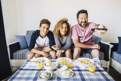 Family watching tv while having food at home