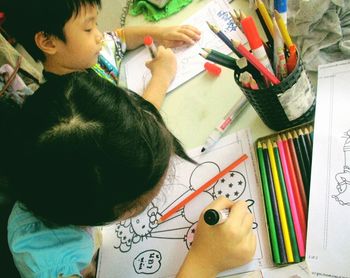 High angle view of people drawing in books on table