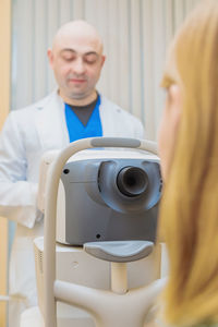 A male ophthalmologist checks the eyesight of a young girl using a modern vision tester