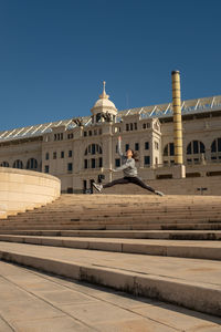 Man sitting outside temple against sky in city