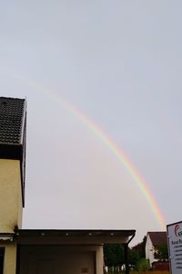 Low angle view of rainbow over buildings against sky