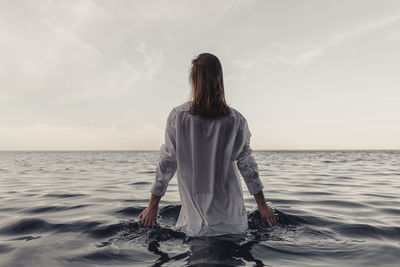 Rear view of woman standing in sea against sky