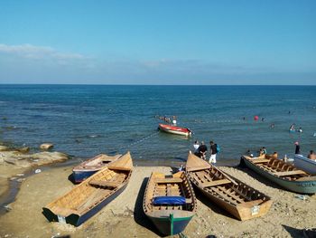 Boats at sea shore against sky