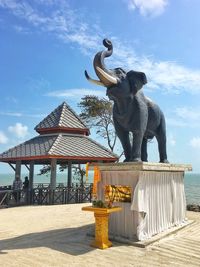 Statue on beach against sky