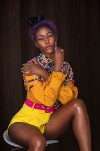 Portrait of young woman standing against black background