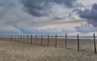 Wooden posts on beach against sky