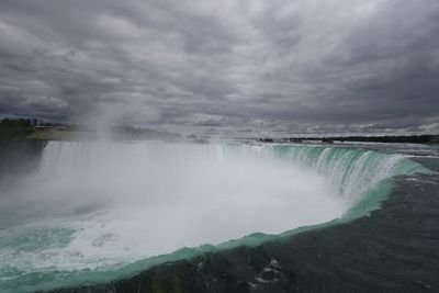 View of waterfall against cloudy sky