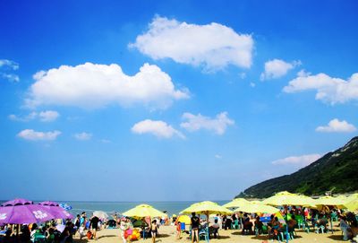 People at beach against blue sky