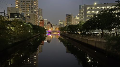 Canal amidst illuminated buildings in city at night