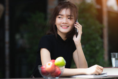 Portrait of a smiling young woman holding apple outdoors