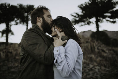 Side view of mid adult couple kissing on field