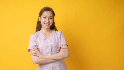 Portrait of teenage girl standing against yellow background