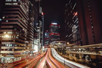 Light trails on road amidst buildings in city at night