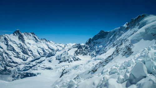 Scenic view of snow mountains against blue sky