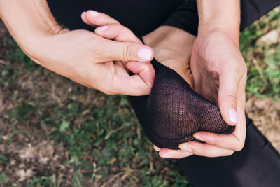 Woman sitting on grass and massages the foot in sock close-up. pain or cramping in the foot