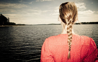 Rear view of woman standing against lake during sunset