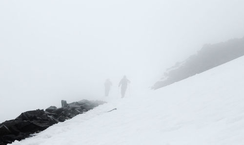 Man walking on snow covered landscape in foggy weather