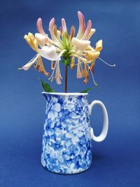 Close-up of white flower vase against blue background