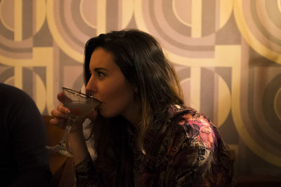 Close-up of woman having cocktail against wall at restaurant