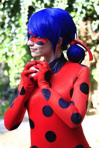 Young woman with blue hair wearing red costume looking away while standing outdoors