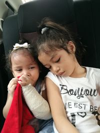 Girl with injured hand sitting by sister in car