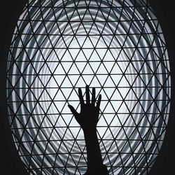 Close-up of silhouette hand on metal grate