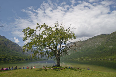 People by lake against sky