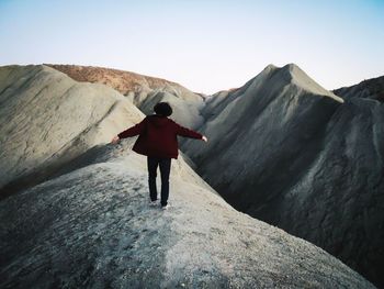 Rear view of man standing on cliff against mountain