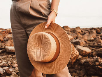 Midsection of woman holding hat