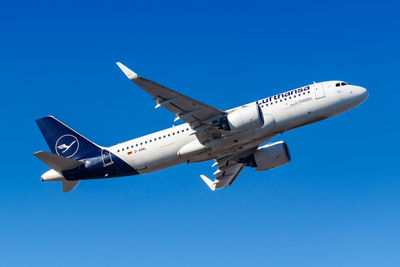 Low angle view of airplane flying against clear blue sky