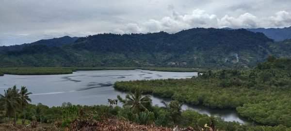 Scenic view of river by mountains against sky
