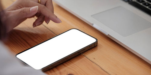 Low angle view of hand using mobile phone on table