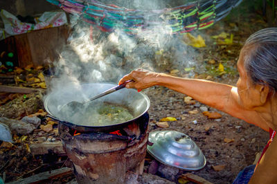 Side view of woman preparing food in yard