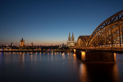 Hohenzollern bridge by cologne cathedral over rhine river in city at dusk